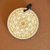 Anhänger aus Holz, graviert mit einem Mandala-Motiv.